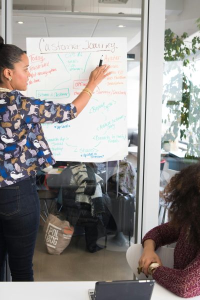 Two women collaborating on project strategy using notes in modern office.